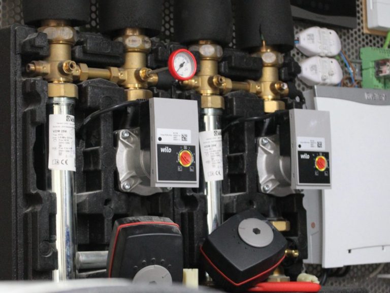 Drei Heizungsumwälzpumpen mit Ventilen an einer Wand montiert.